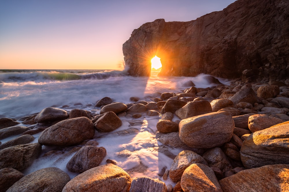 the sun is setting over a rocky beach