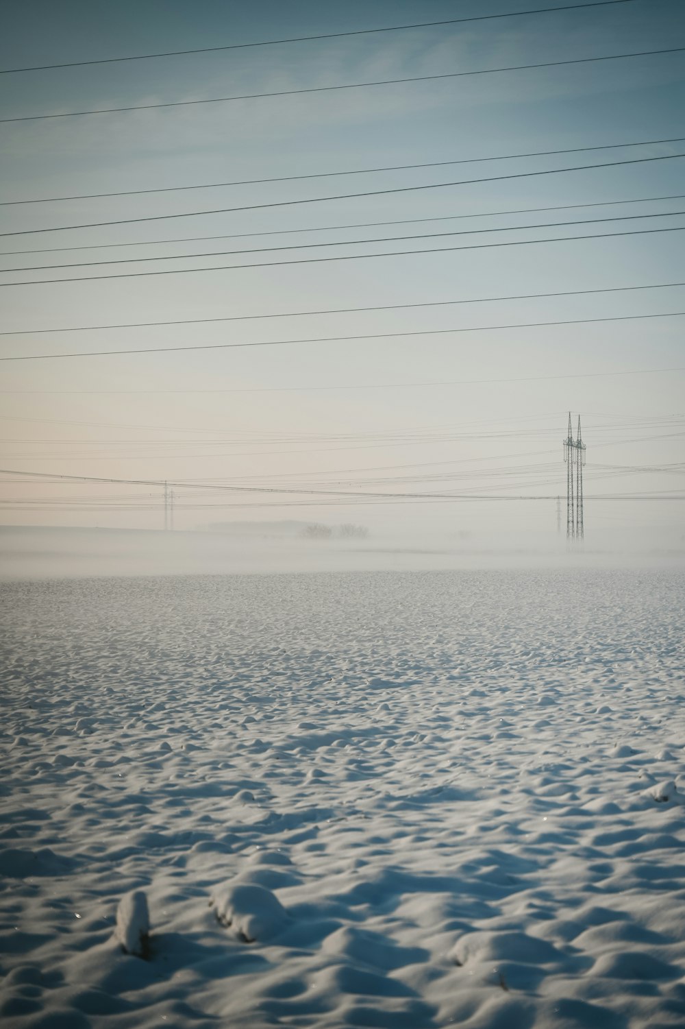 a snowy field with power lines in the distance