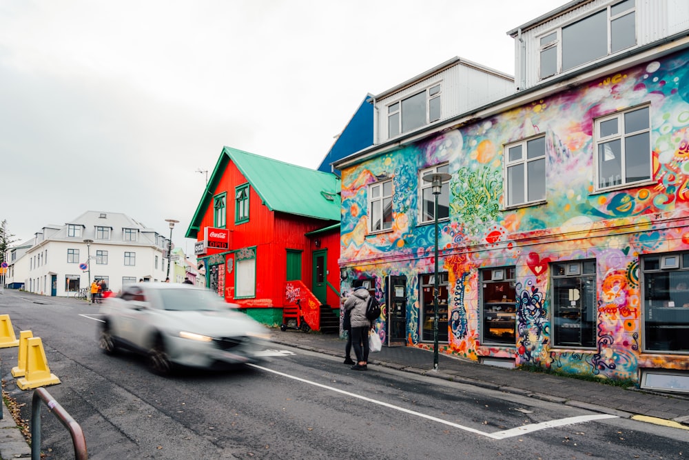 a car driving down a street next to a colorful building