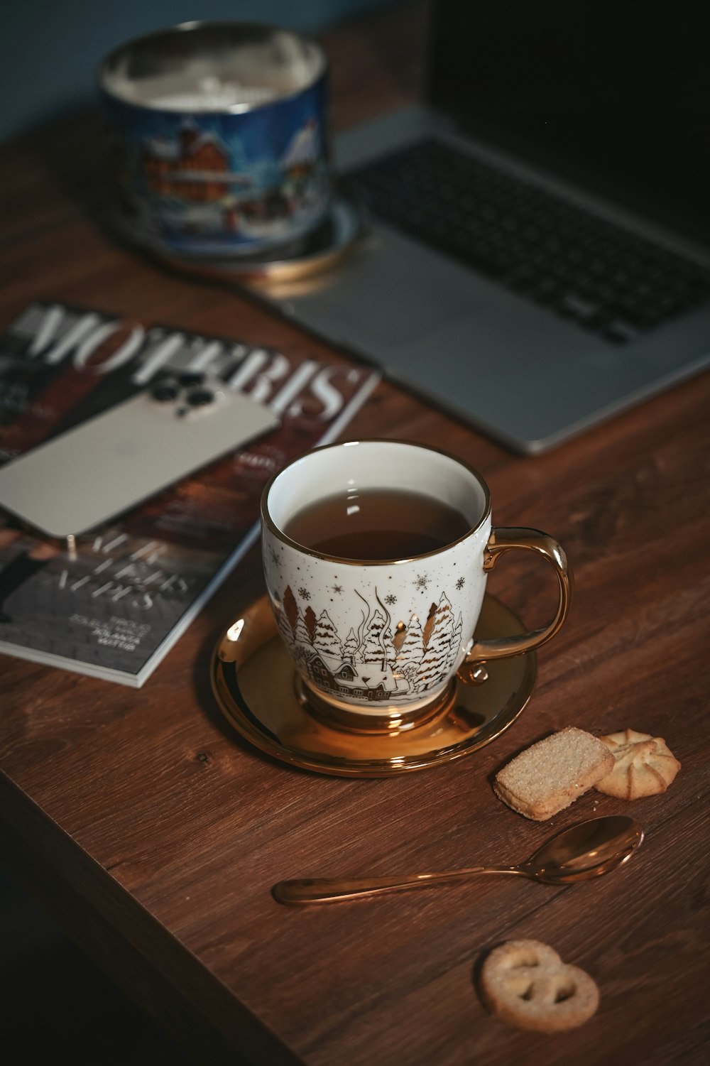 a cup of tea on a saucer next to a laptop