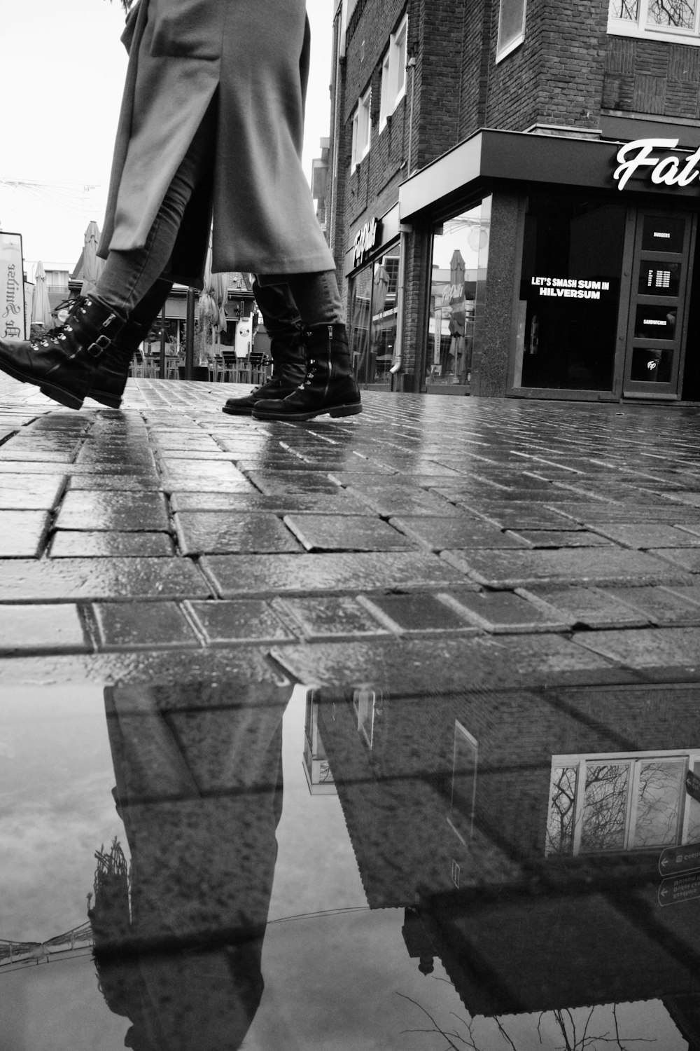 a couple of people walking down a street next to a puddle