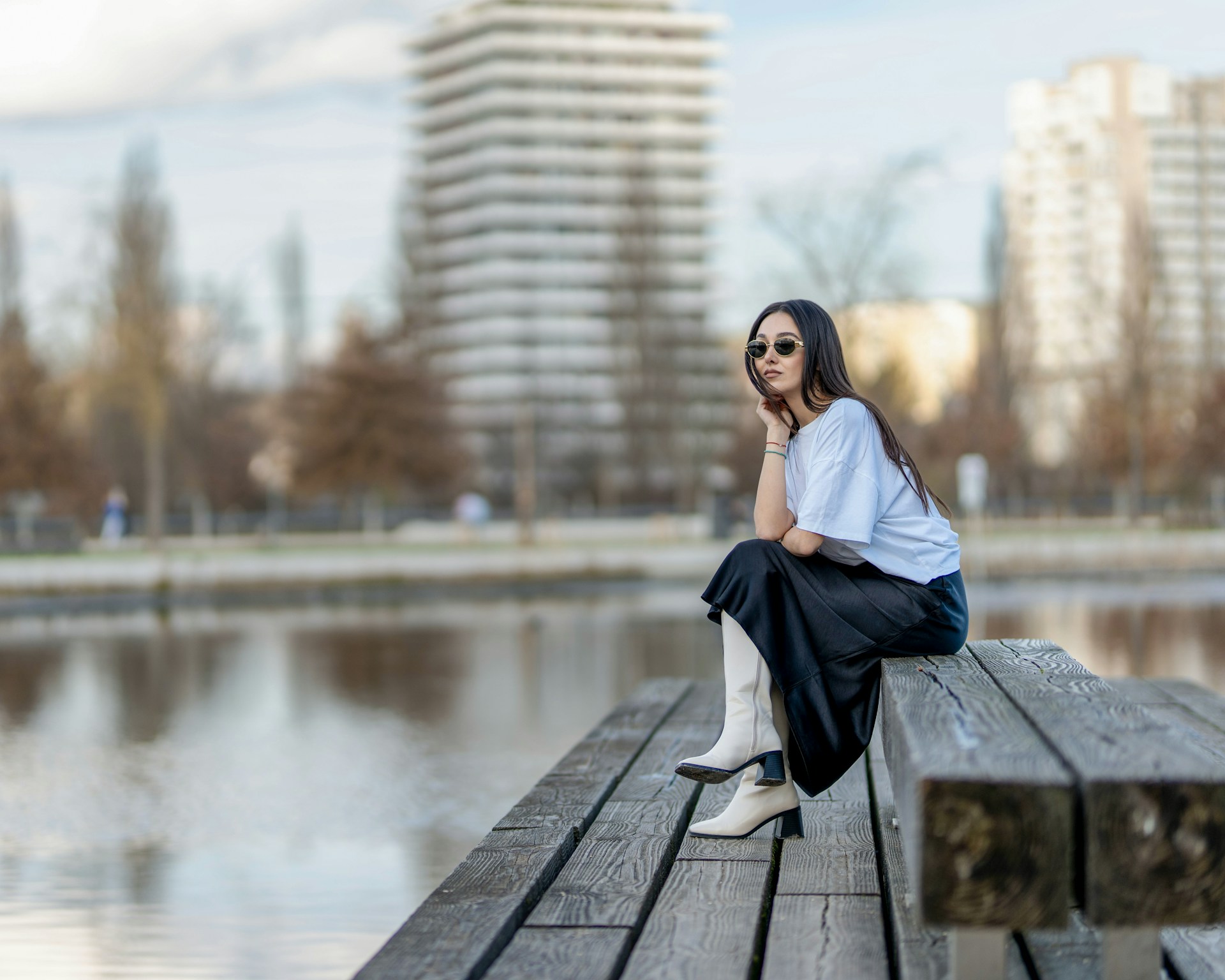 a woman sitting on a wooden bench next to a body of water