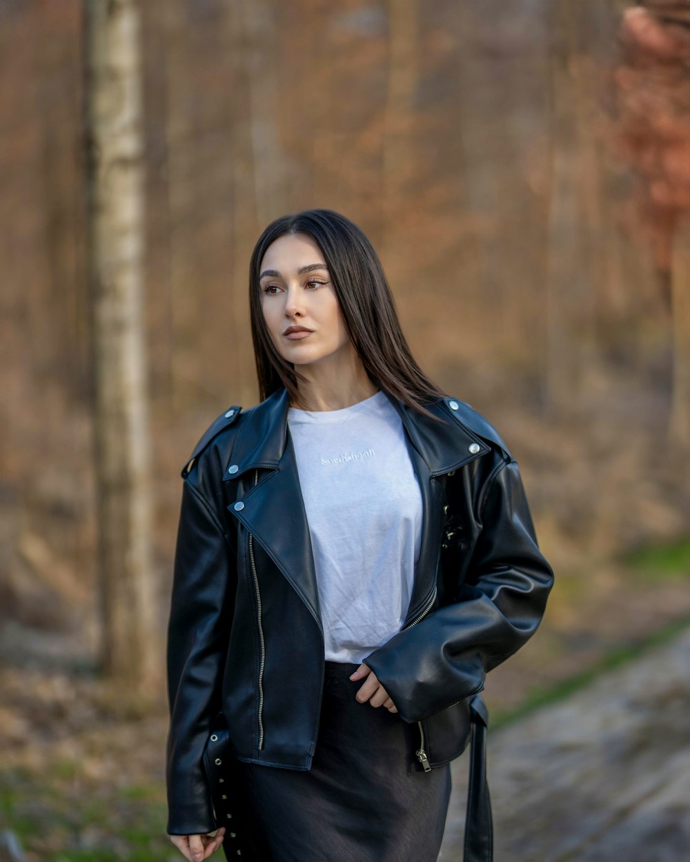 a woman wearing a black leather jacket and skirt