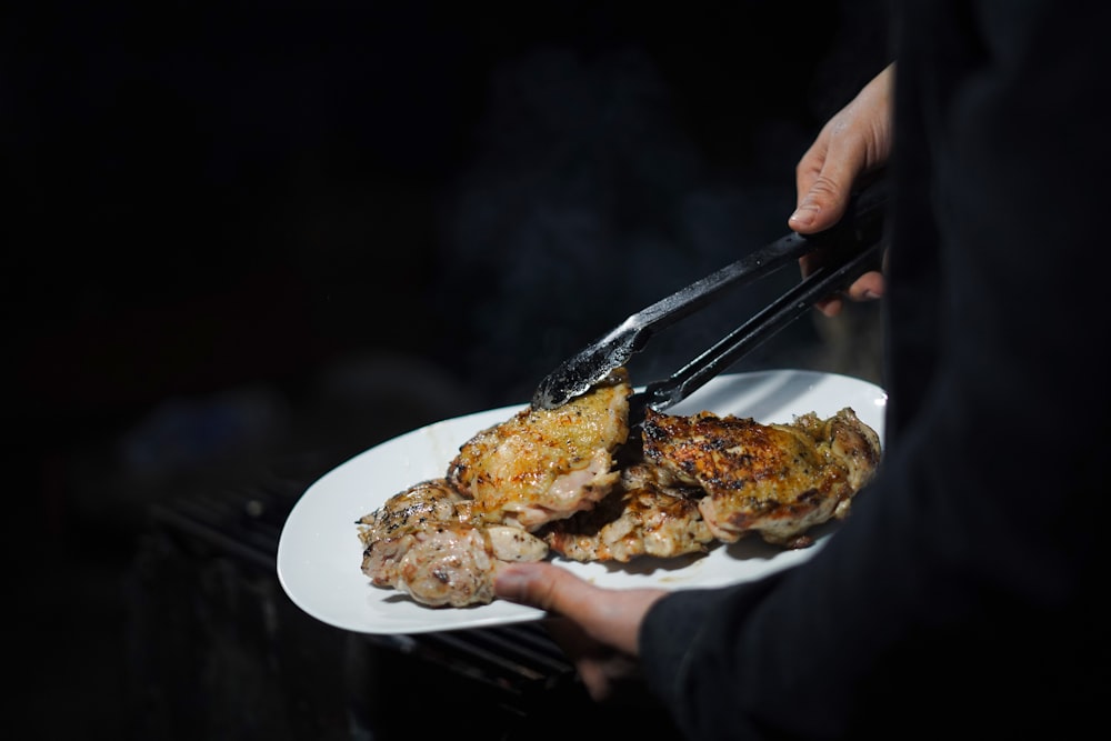 a person holding a plate of food on a grill