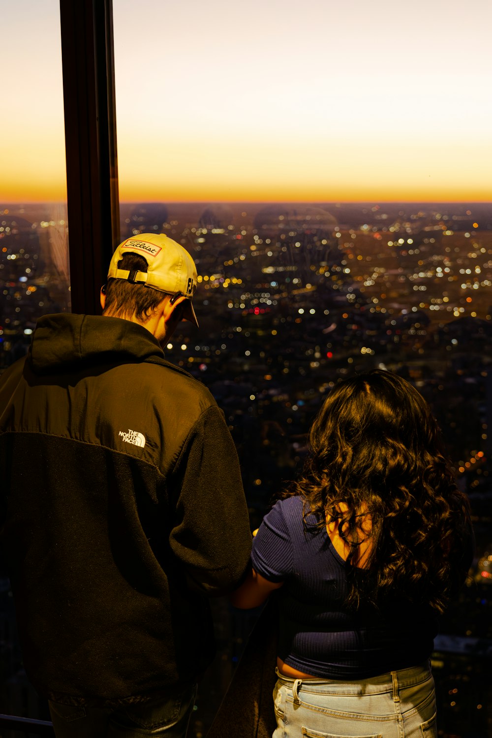 a man and a woman standing on top of a tall building