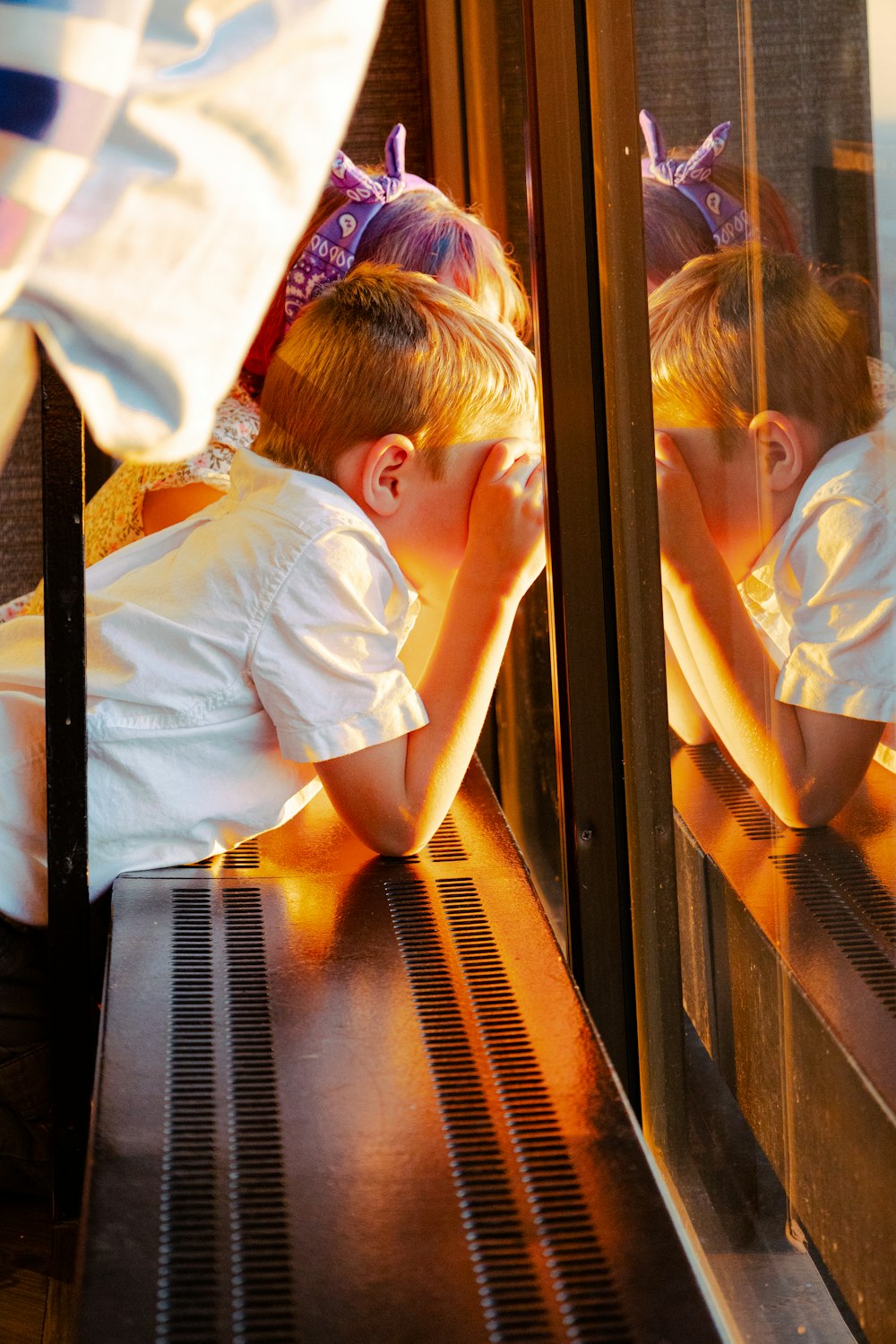 a young boy sitting on a bench next to a window