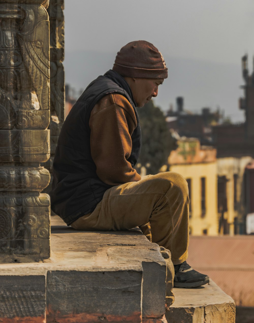 a man sitting on top of a stone pillar