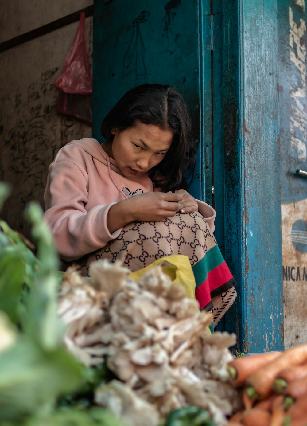 a woman standing next to a pile of vegetables