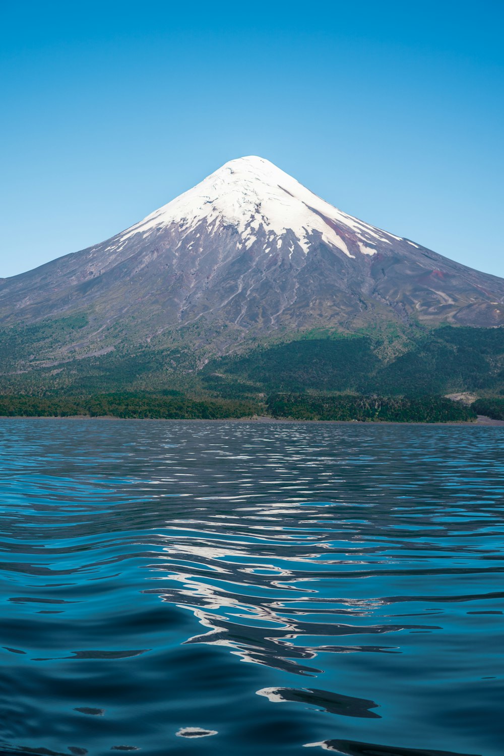 a mountain with a snow capped peak is seen from the water