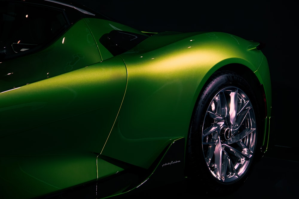 a green sports car parked in a dark room