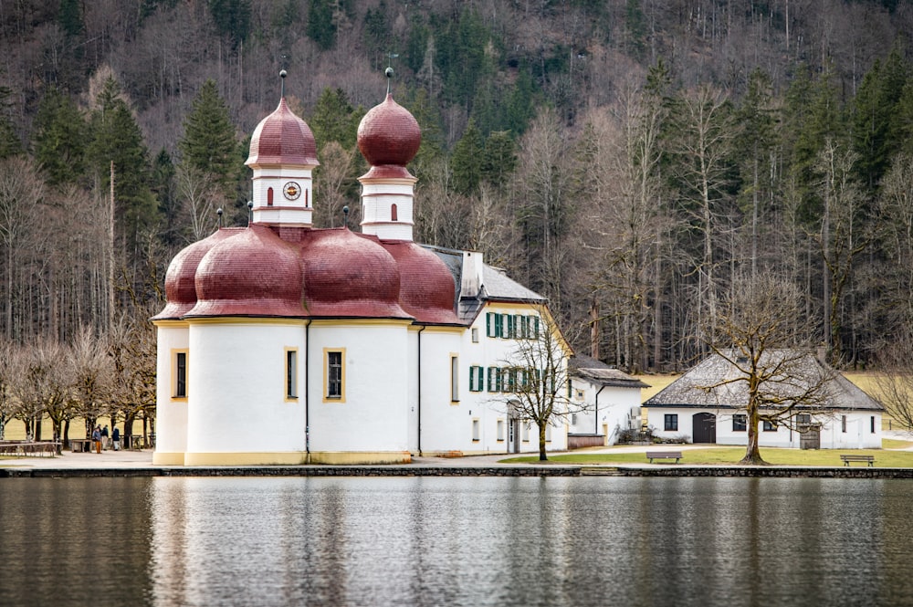 a large white building with a red roof next to a body of water