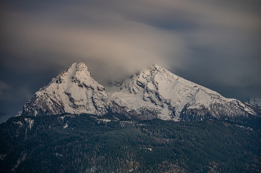 a mountain covered in snow under a cloudy sky