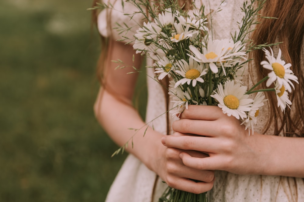 a close up of a person holding a bouquet of flowers