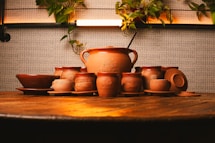 a wooden table topped with lots of brown pottery