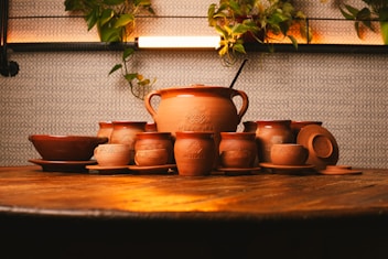 a wooden table topped with lots of brown pottery