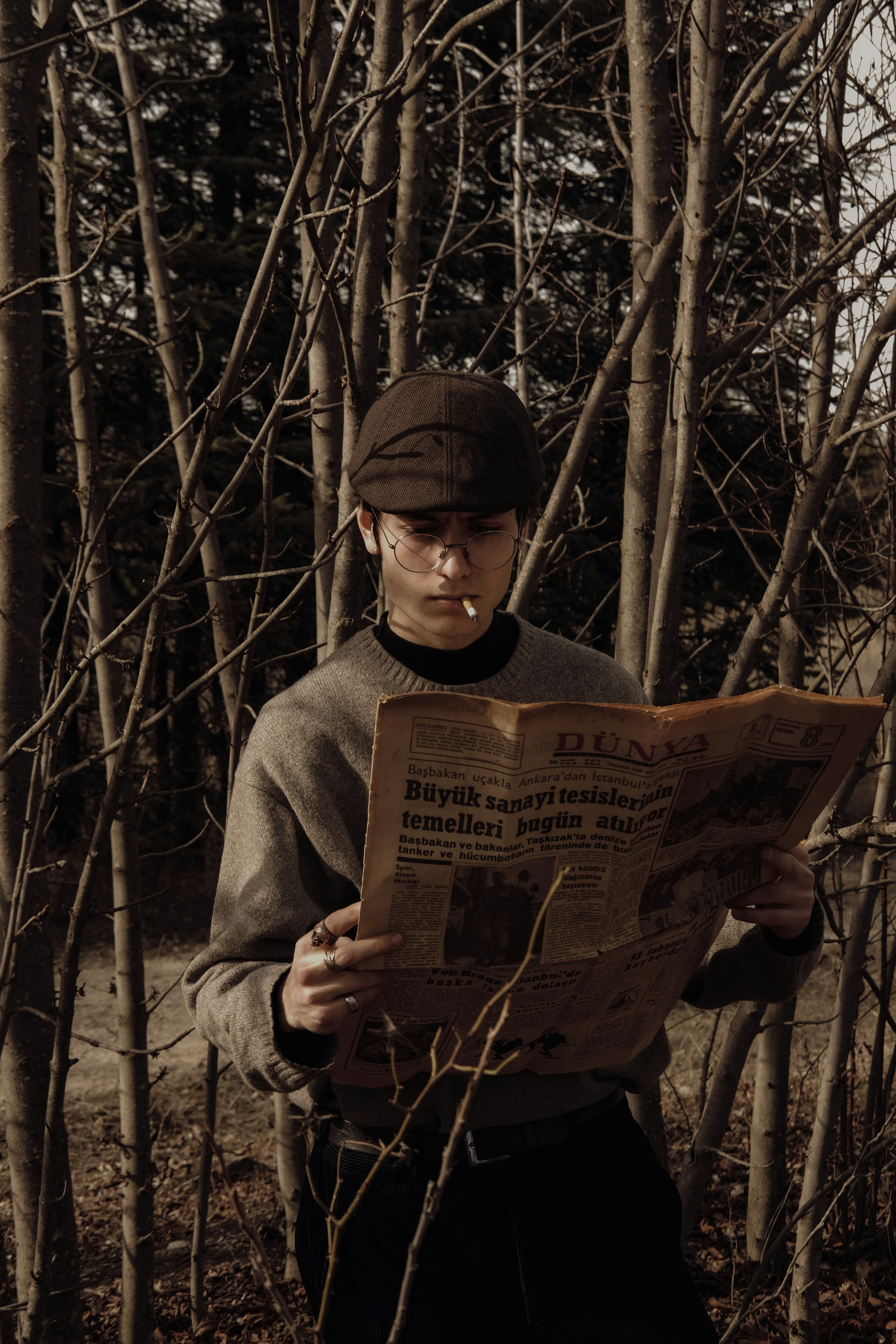 um homem parado na floresta lendo um jornal