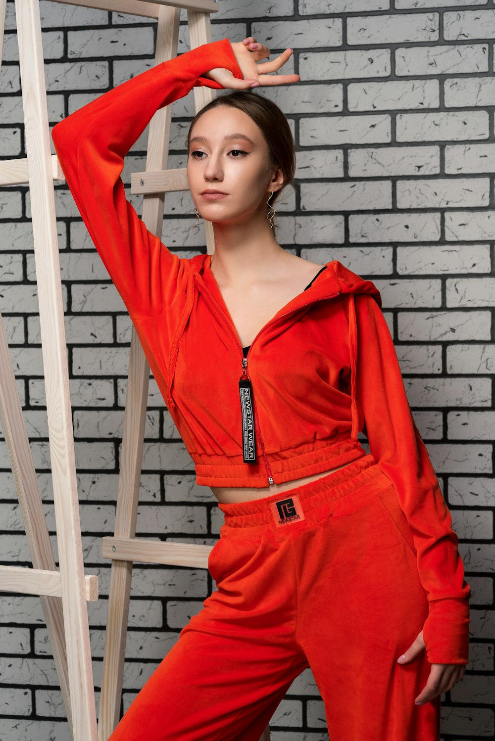 a woman in an orange outfit leaning against a ladder