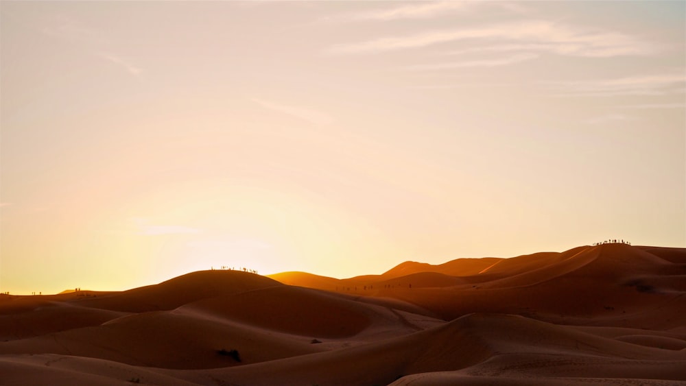 the sun is setting in the desert with sand dunes