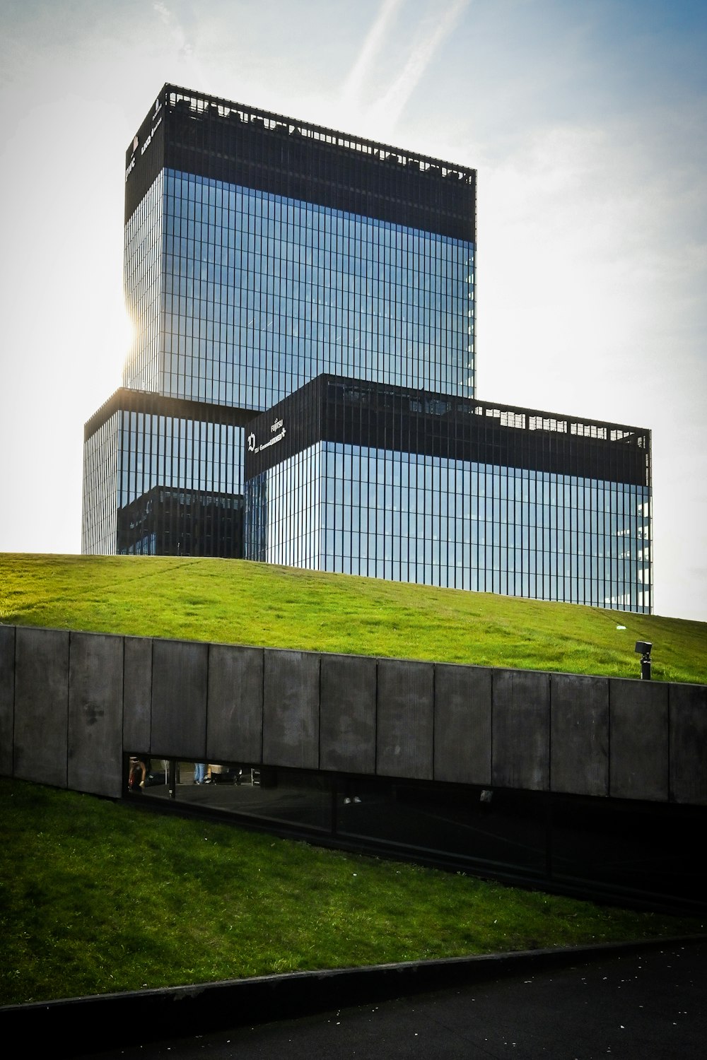 a building with a green roof and a grassy field in front of it