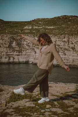a woman standing on top of a rock near a body of water