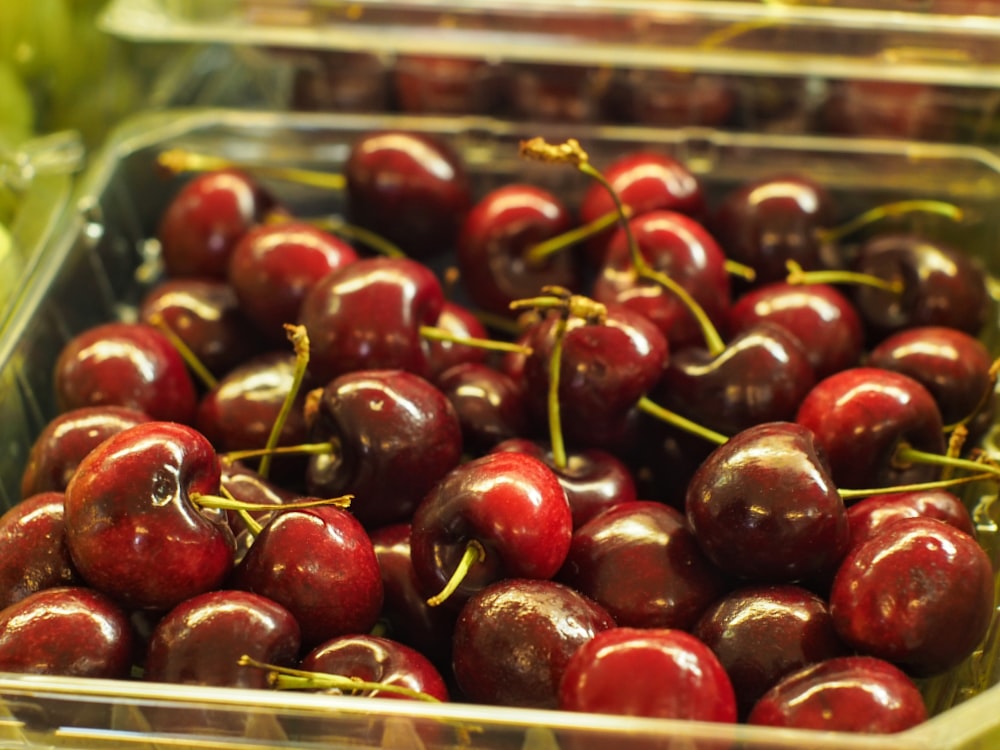 un recipiente de plástico lleno de muchas cerezas