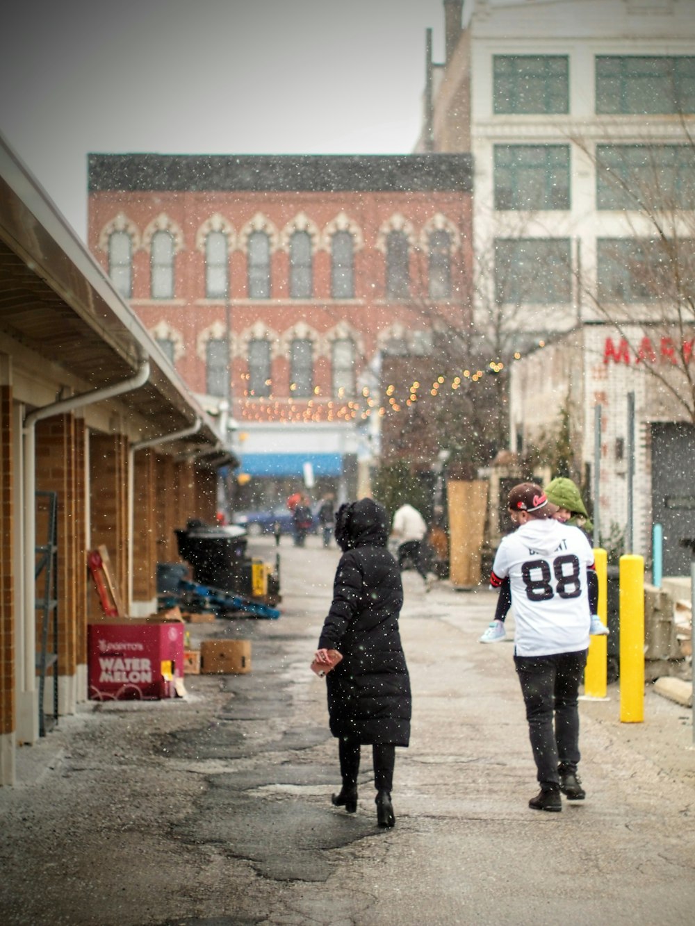 two people walking down a street in the snow