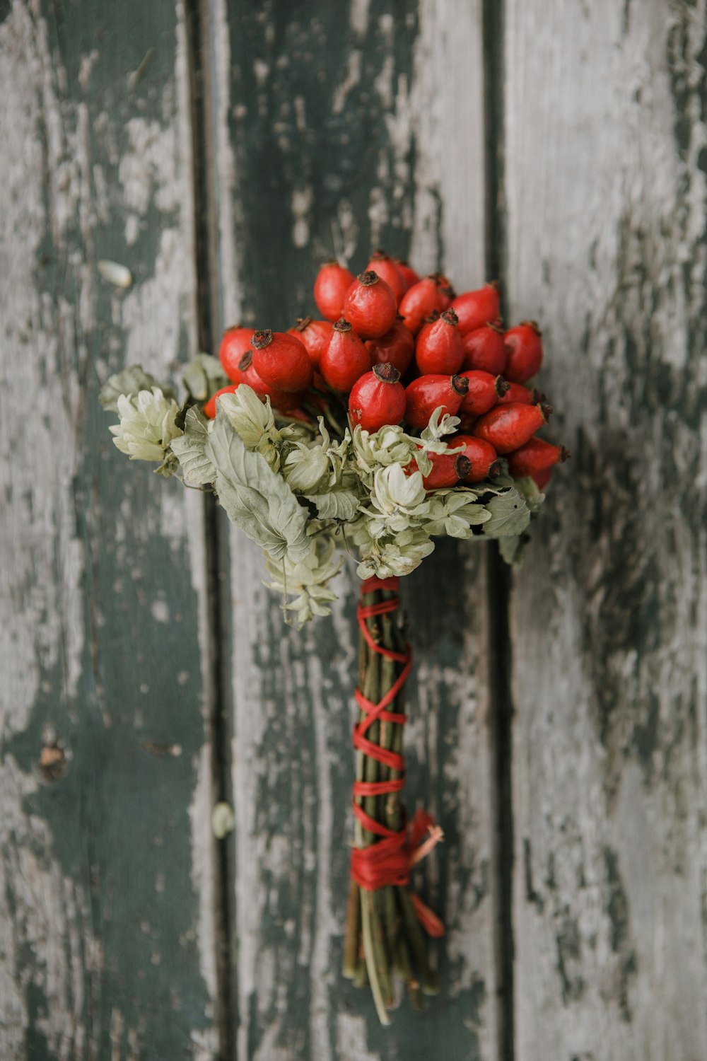 a bouquet of red flowers sitting on top of a wooden wall