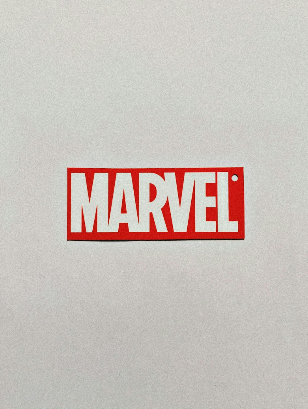 a red and white sticker with the word marvel on it