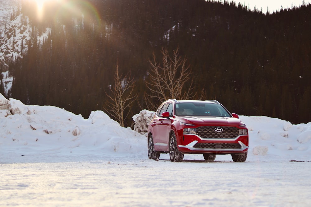 a red car is parked in the snow