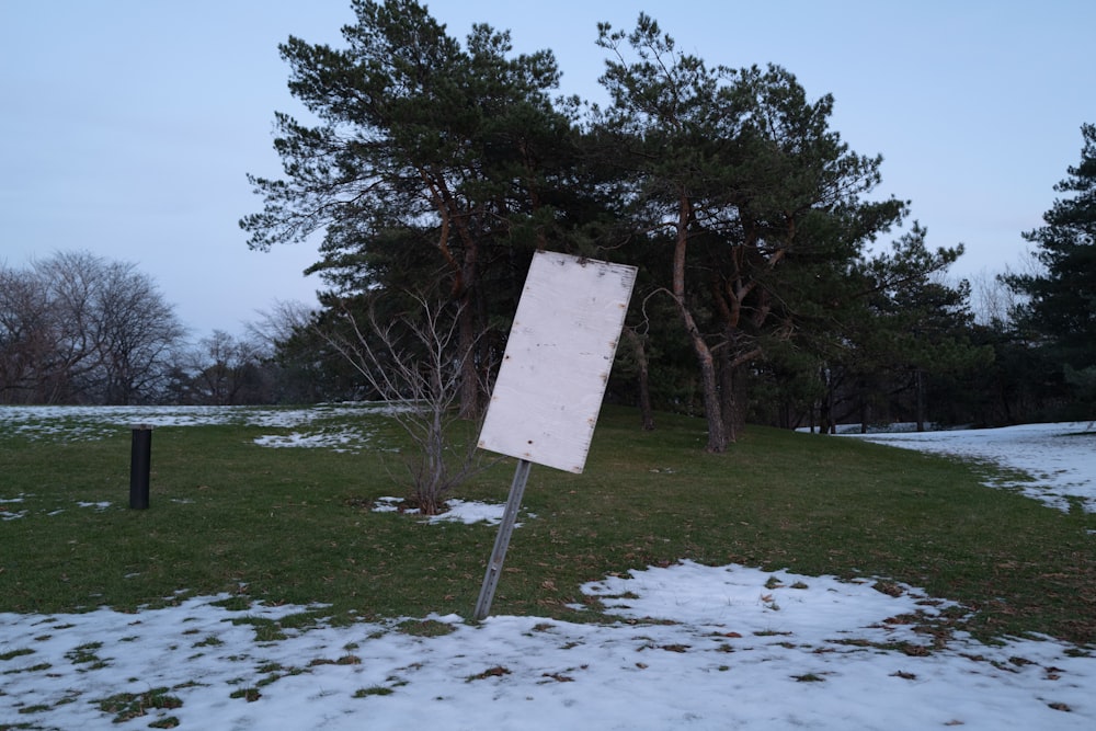 a white sign sitting in the middle of a snow covered field