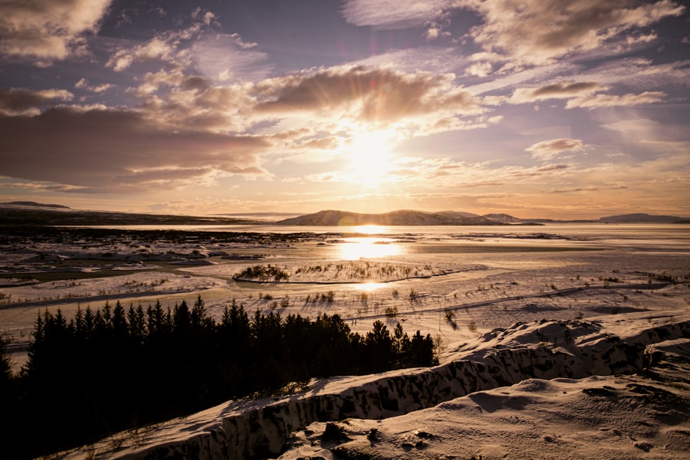 o sol está se pondo sobre uma paisagem nevada
