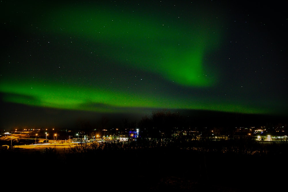 a bright green aurora bore over a city at night