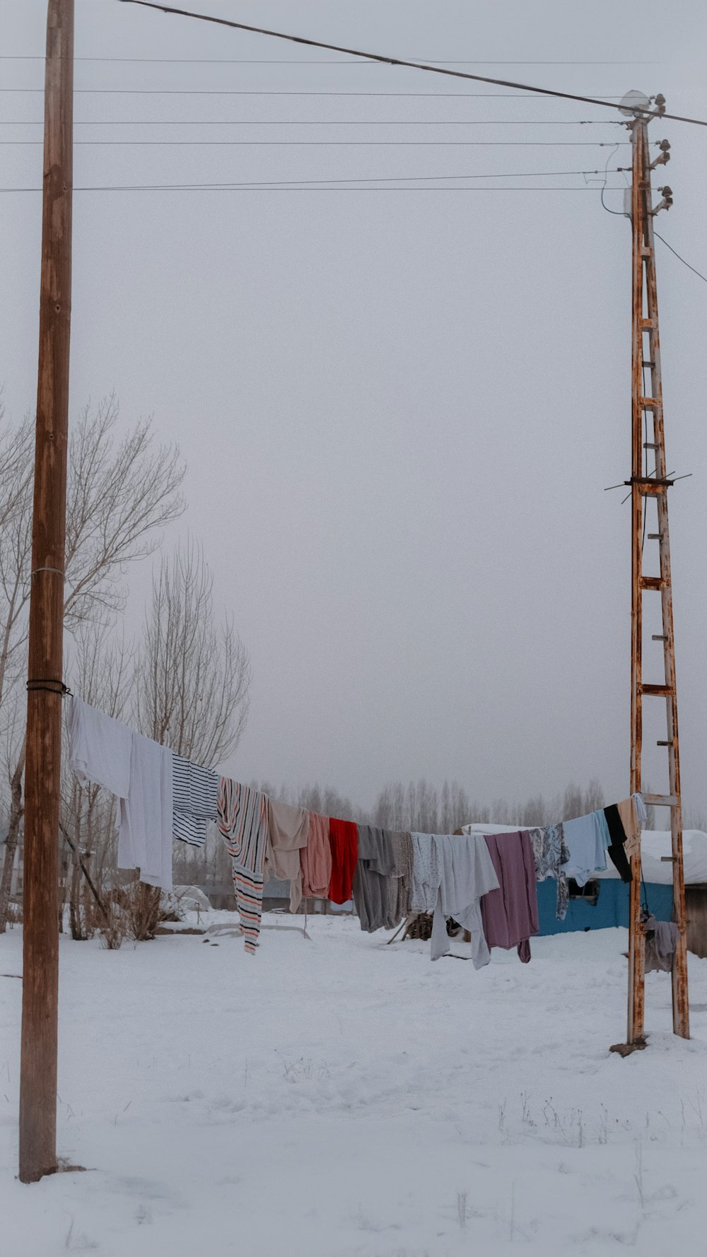 una fila di vestiti appesi a una corda per stendere i panni nella neve
