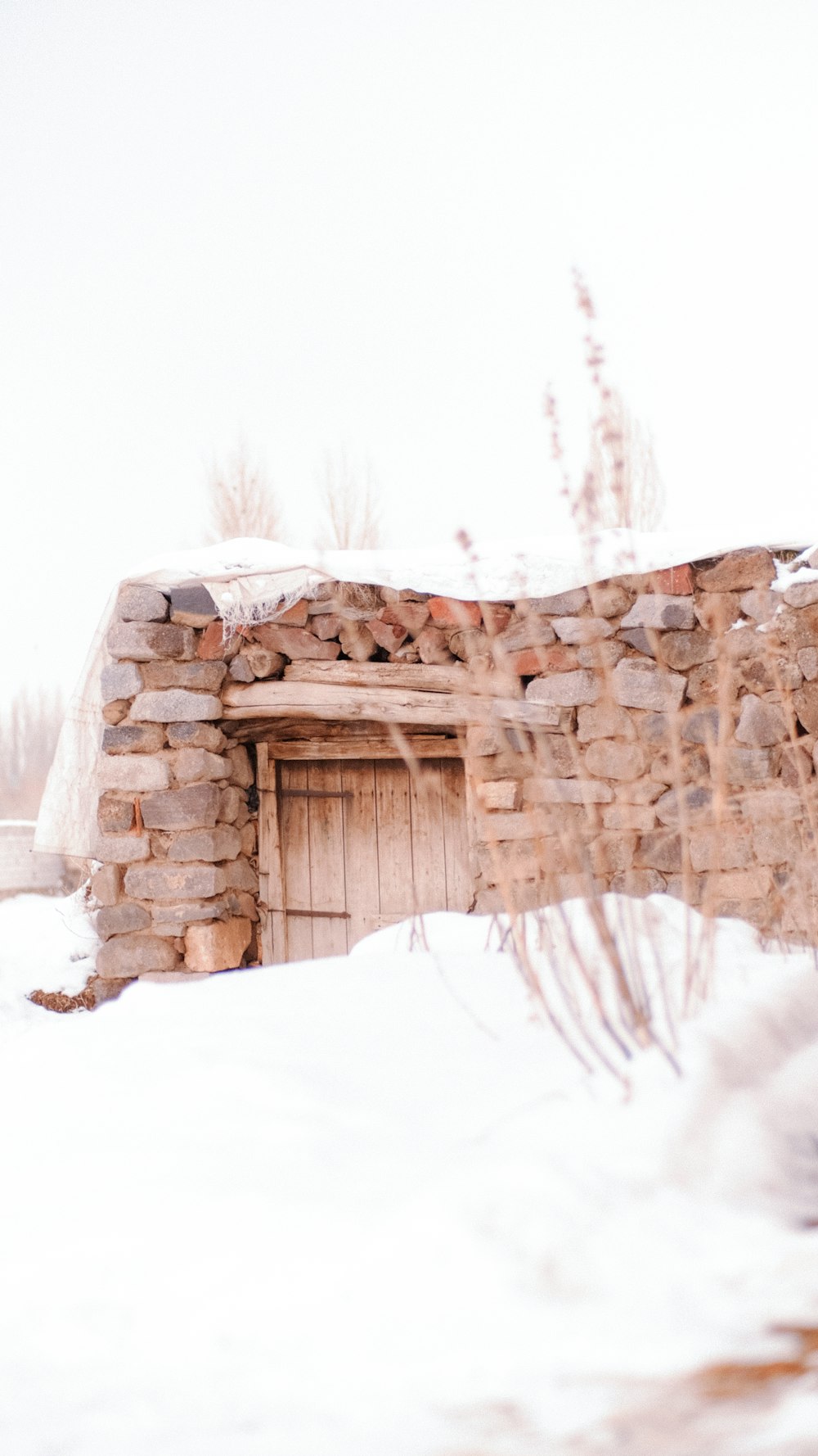 a snow covered field with a small building in the background