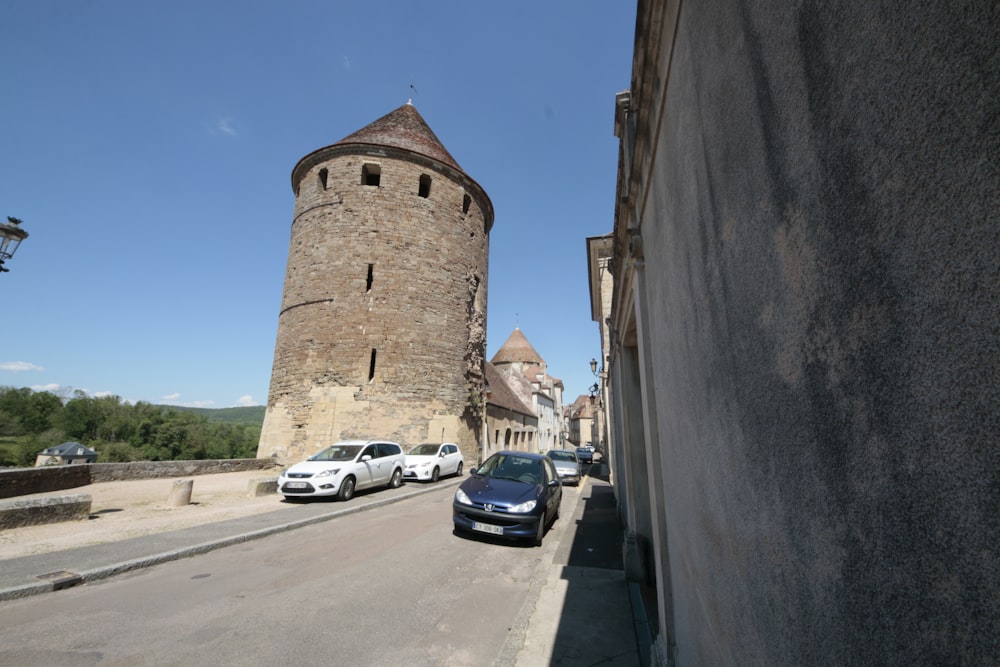 cars parked on the side of a road next to a tall tower