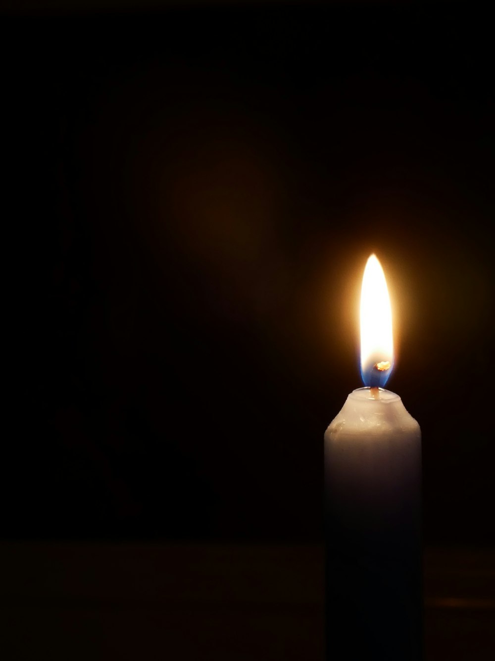 a lit candle with a dark background