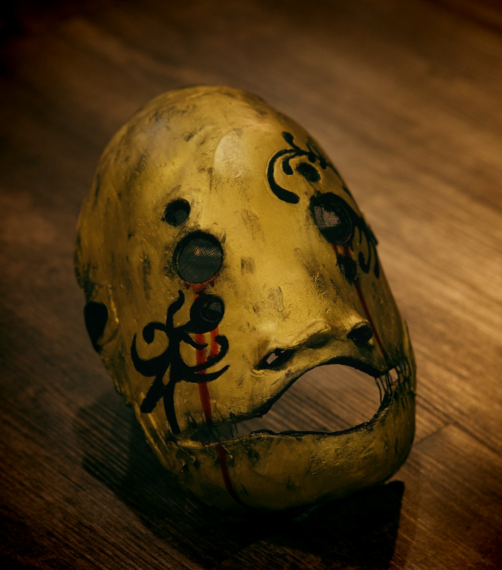 a yellow mask with black and red designs on it