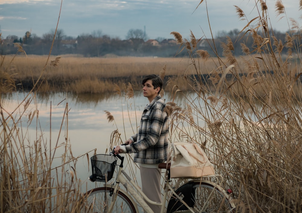 a man standing next to a bike next to a body of water