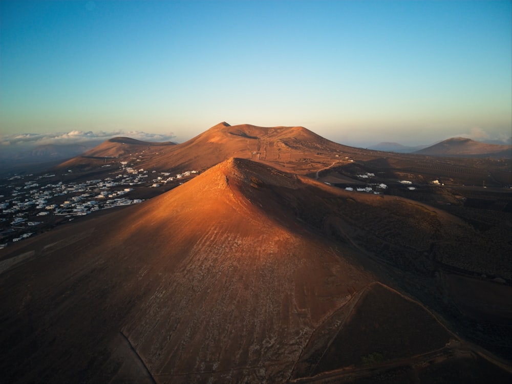 an aerial view of a mountain with a town in the distance