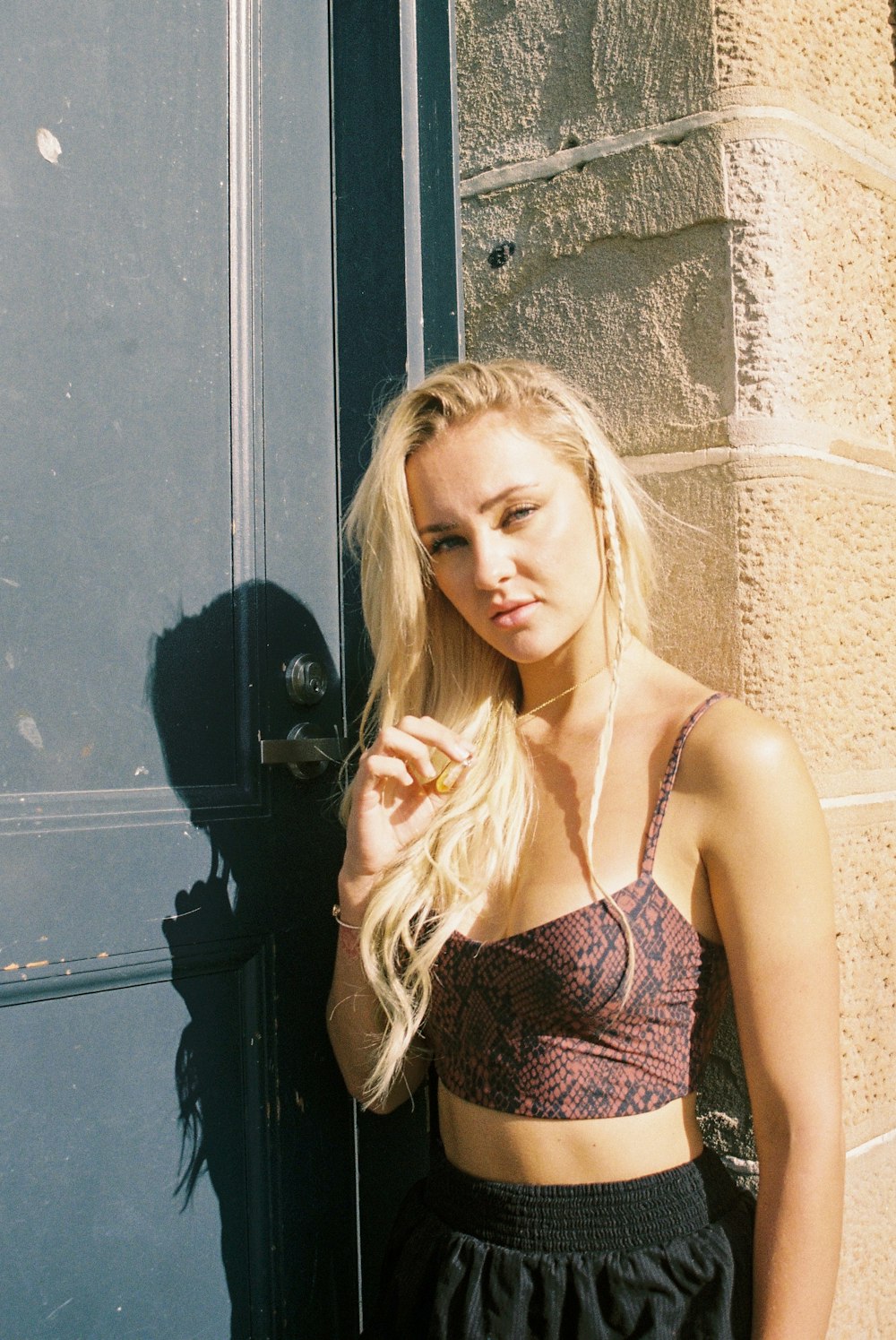 a beautiful young blond woman standing next to a door