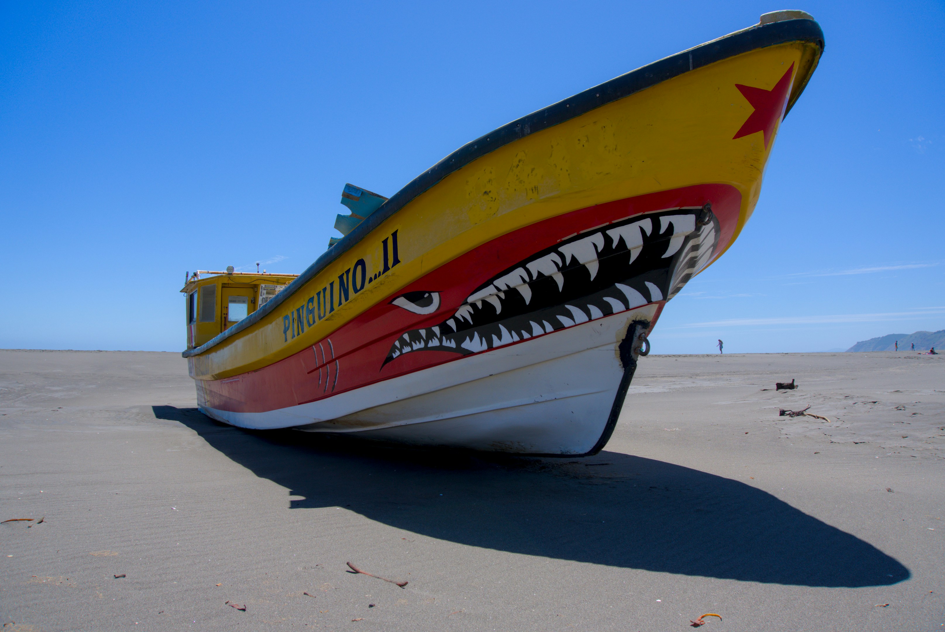 ein gelb-rotes Boot, das auf einem Sandstrand sitzt