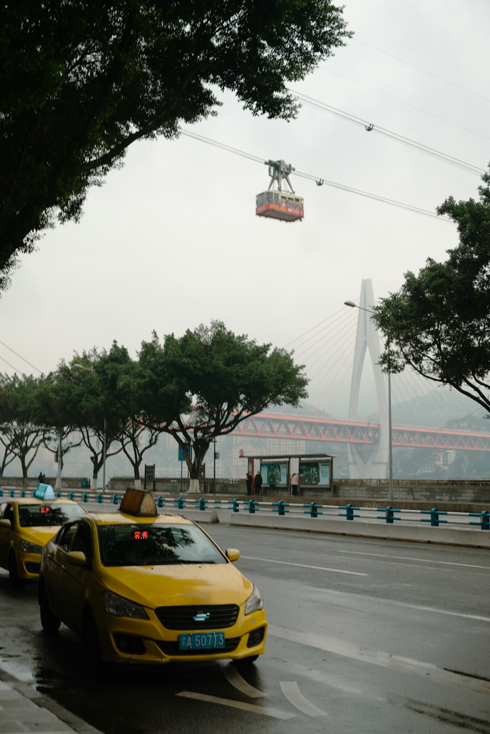 a yellow taxi cab driving down a rain soaked street