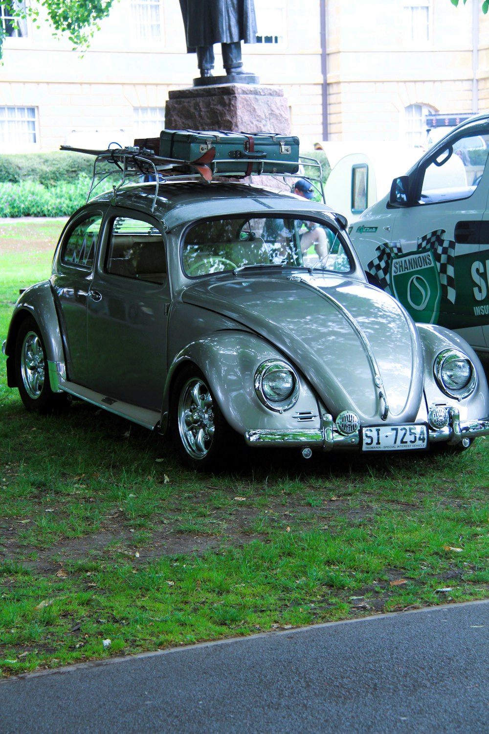 a car with luggage on top of it parked next to a statue