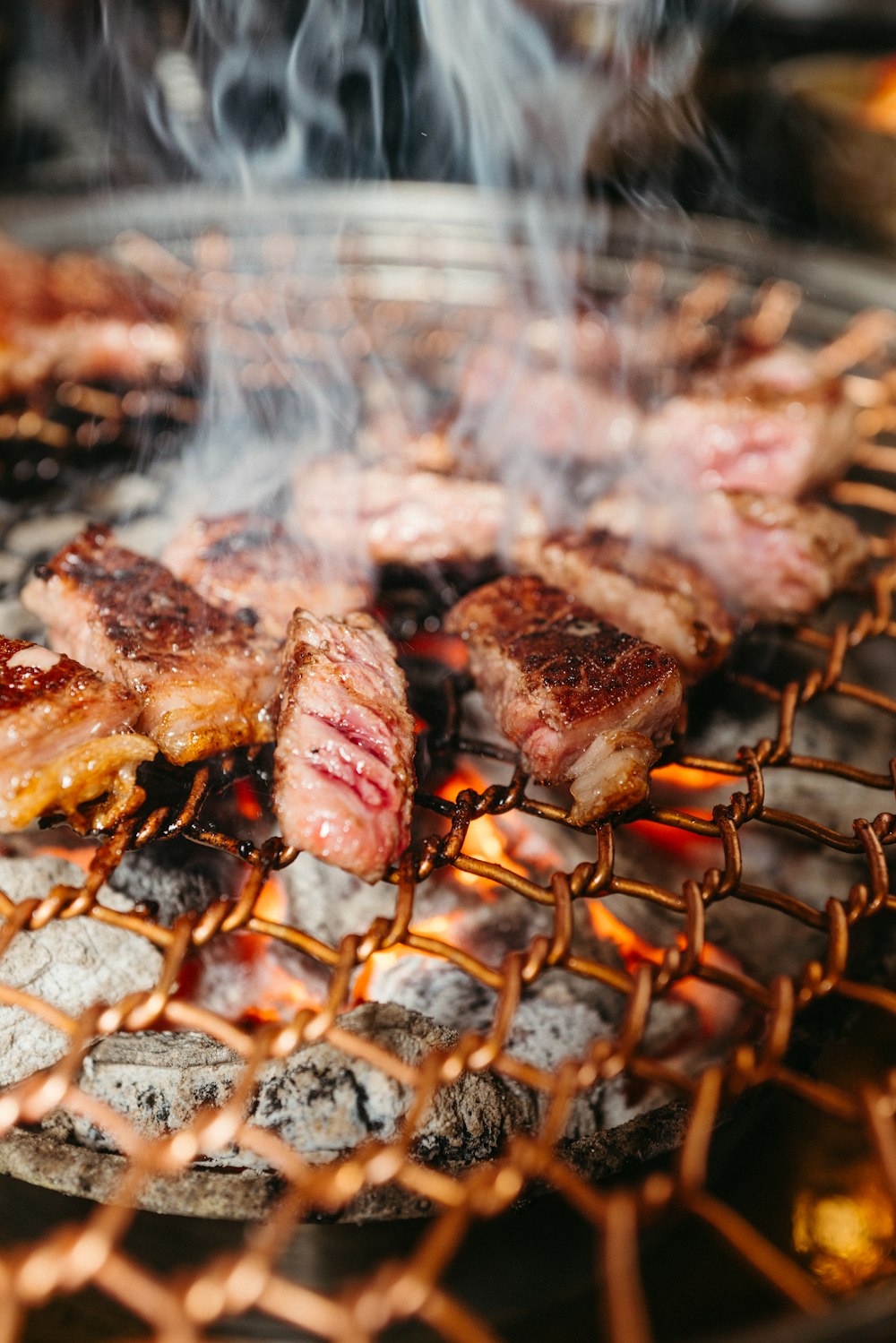 steaks cooking on a grill with smoke coming out of them