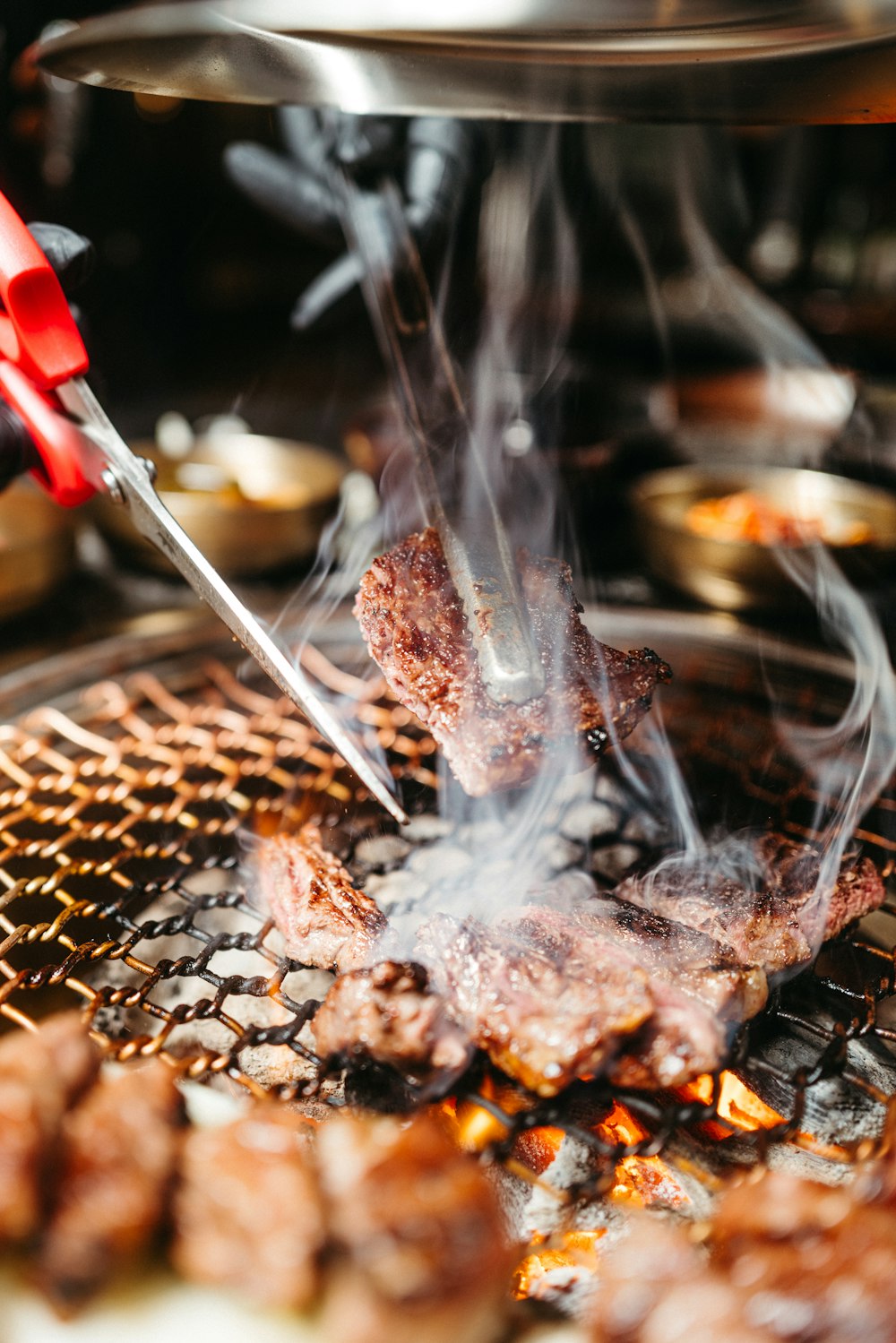 a person grilling meat on a grill with tongs