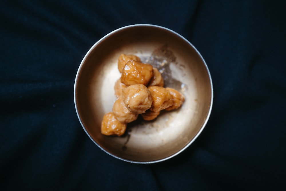 a metal bowl filled with food on top of a black table