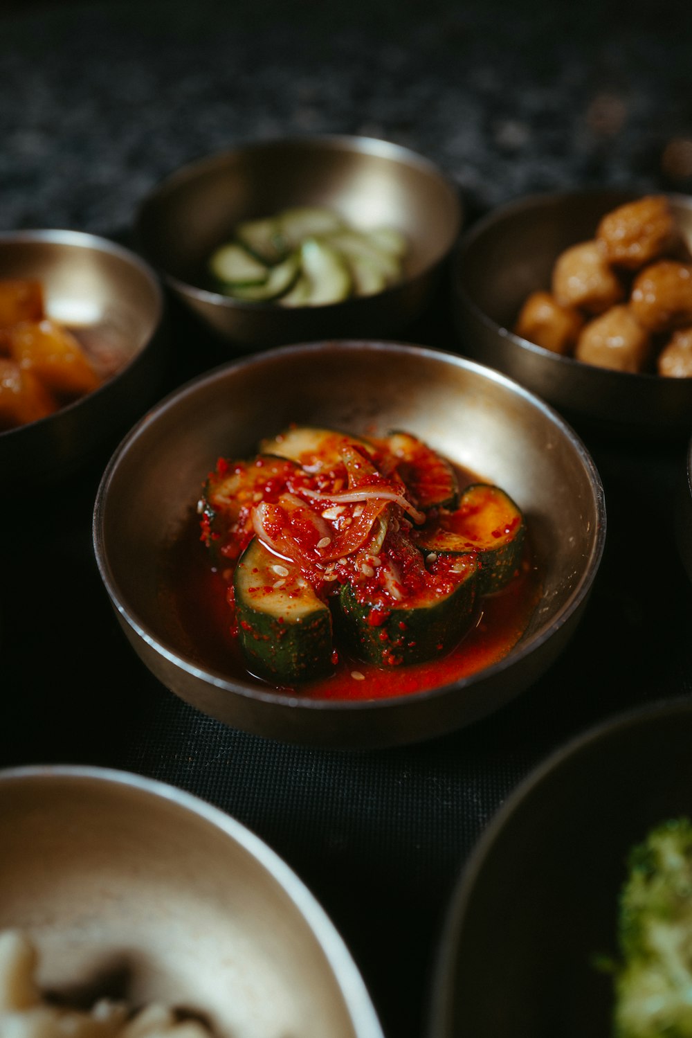 a table topped with metal bowls filled with food