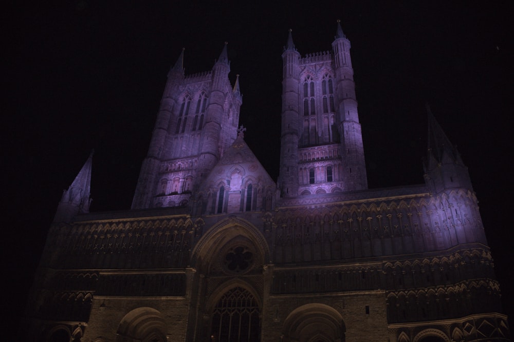 uma grande catedral iluminada à noite com luzes roxas