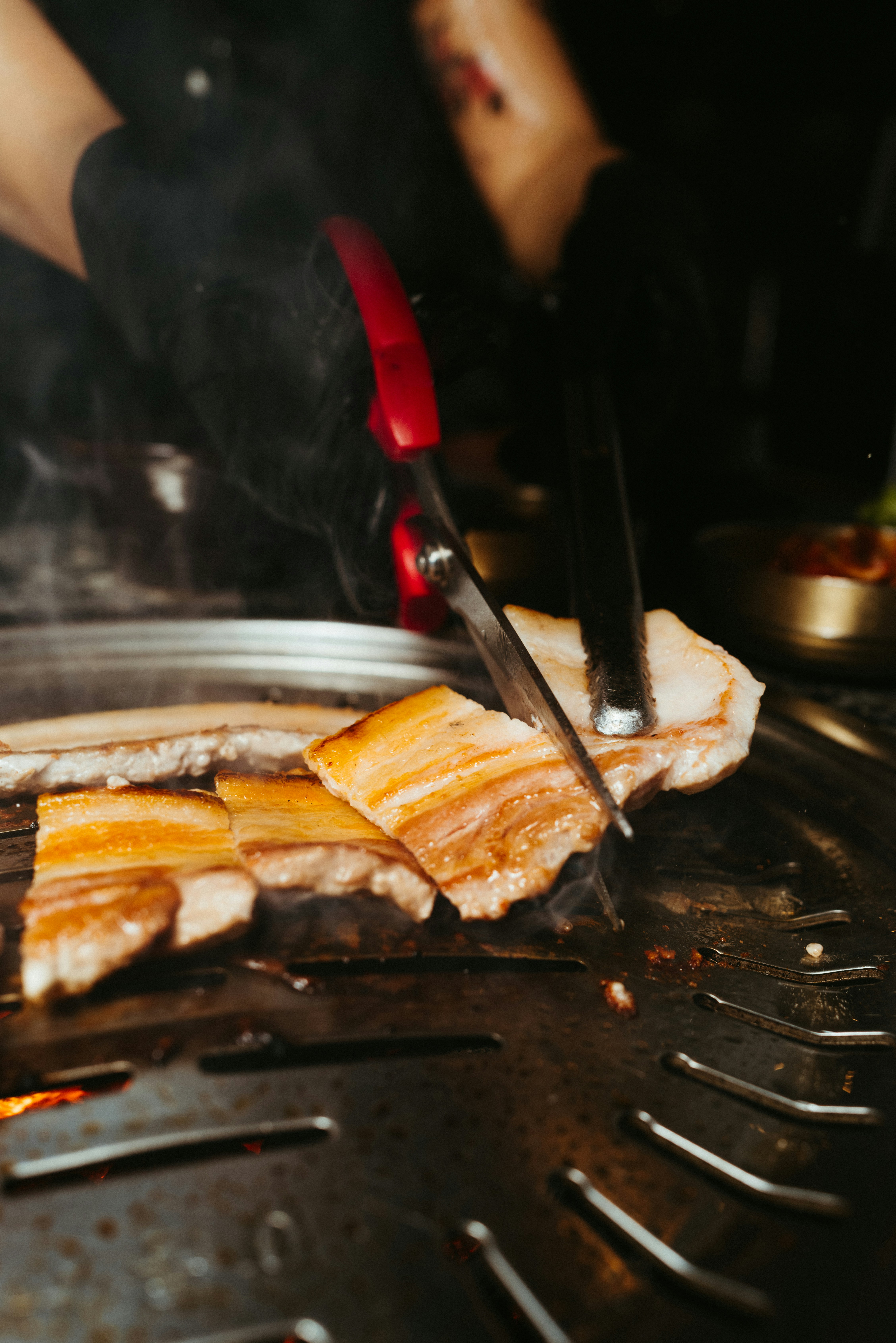 a person cooking food on a grill with tongs
