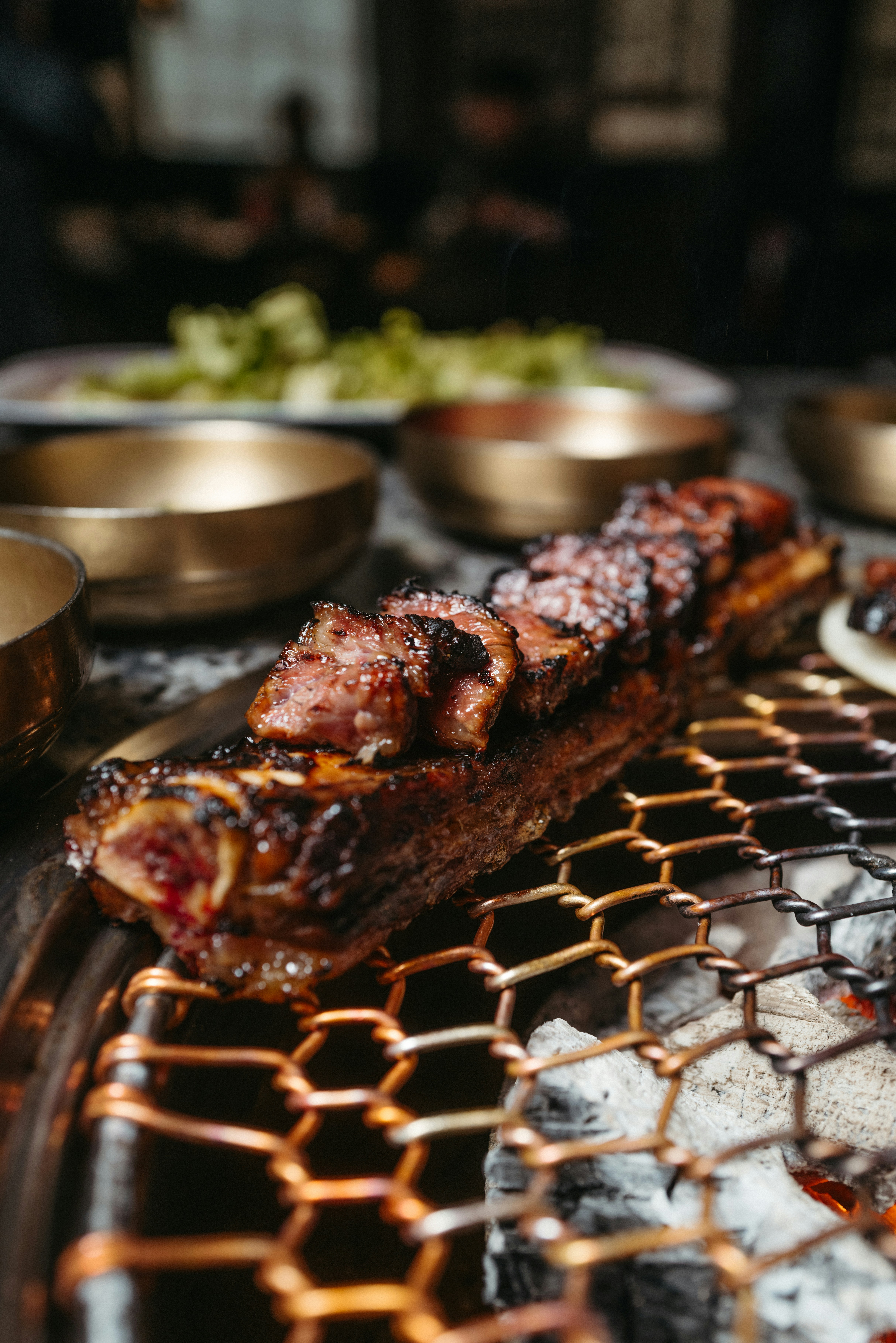 Sizzling BBQ ribs with dark caramelized glaze on wooden board, warm amber kitchen lighting